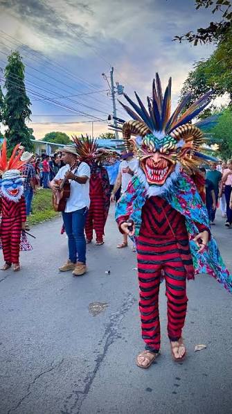 Masked dancers in striped costumes during a festival parade in Tonosí