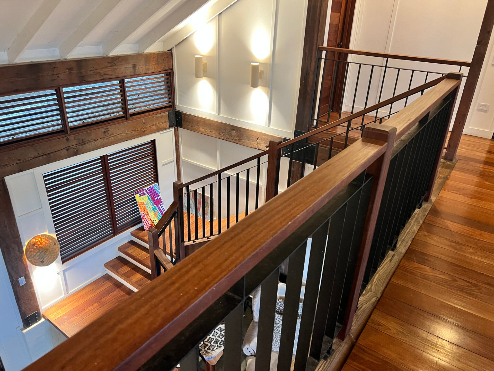 Stairs rising to the upper floor with reclaimed timber beams and louvred shutters