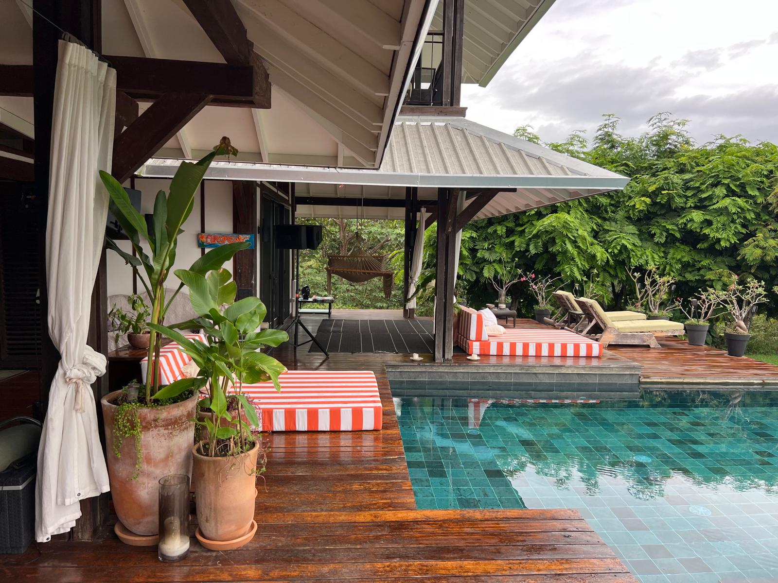Striped daybeds on the wooden deck beside the green-tiled pool