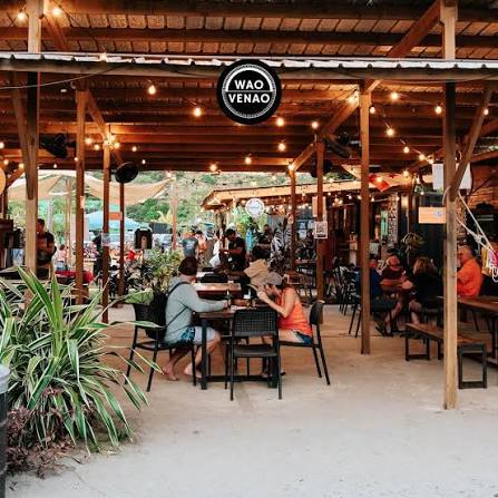 Open air timber dining hall with string lights and guests at WAO Venao