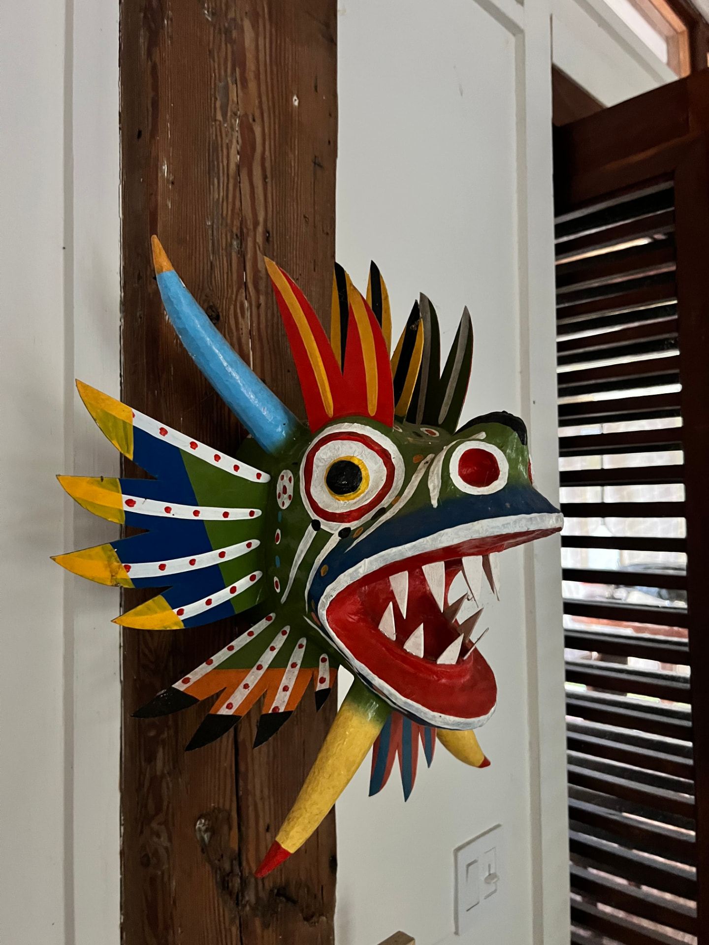 Hand-carved polychrome mask on a timber wall, interior detail