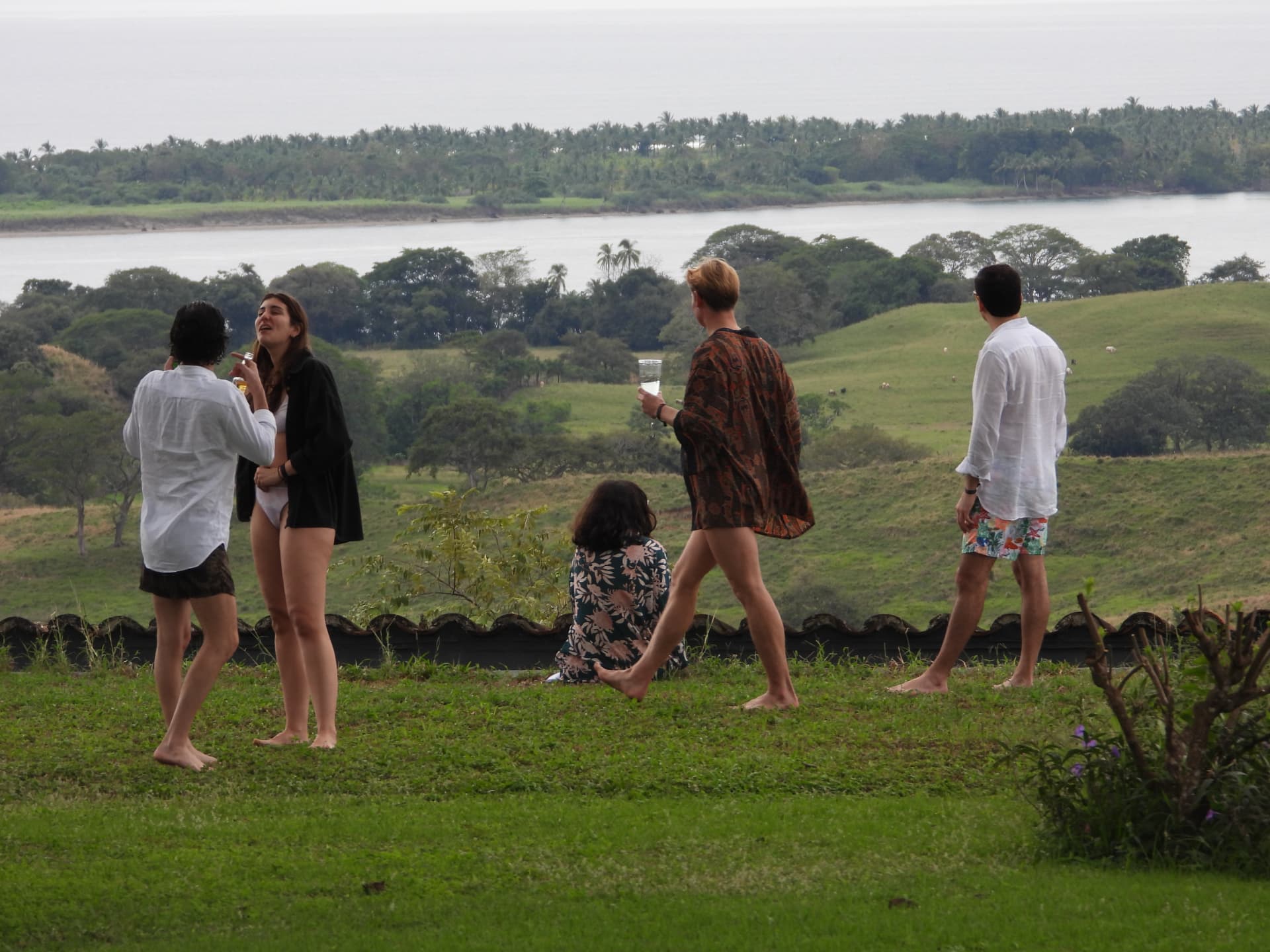 Guests laughing and gathering on the lawn with the lake and hills beyond