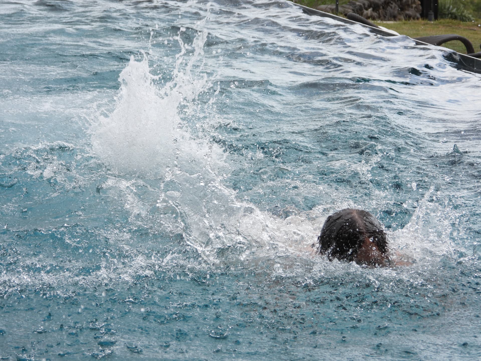 A swimmer splashing through the turquoise pool water