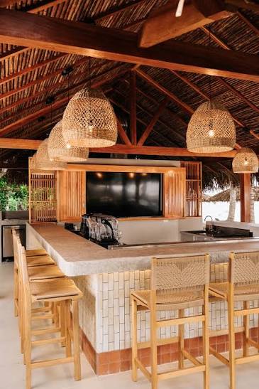 Rattan pendant lights above a tiled bar counter under a thatched roof at Villa Marina Beach Bar