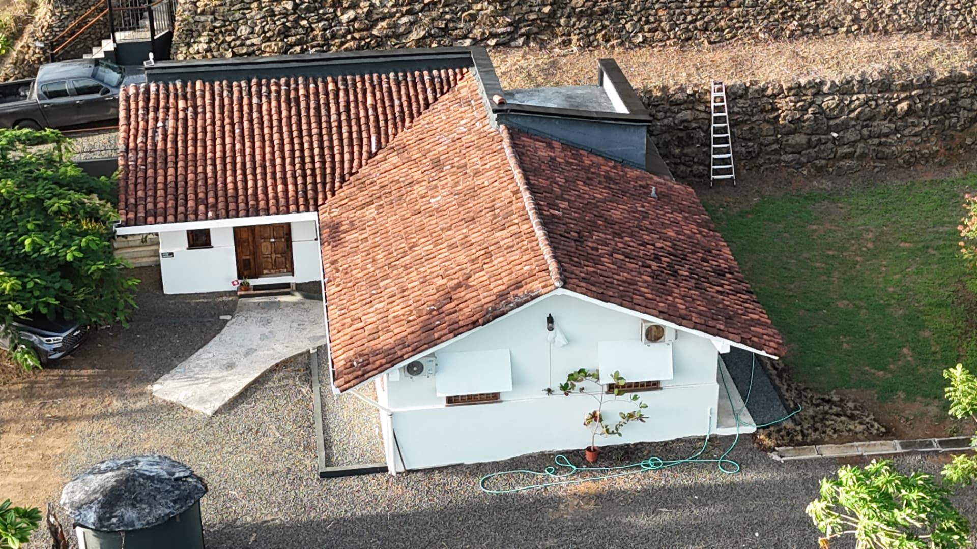 Aerial view of Casa Abuela with terracotta tile roofs, white walls, timber door and a stone retaining wall behind