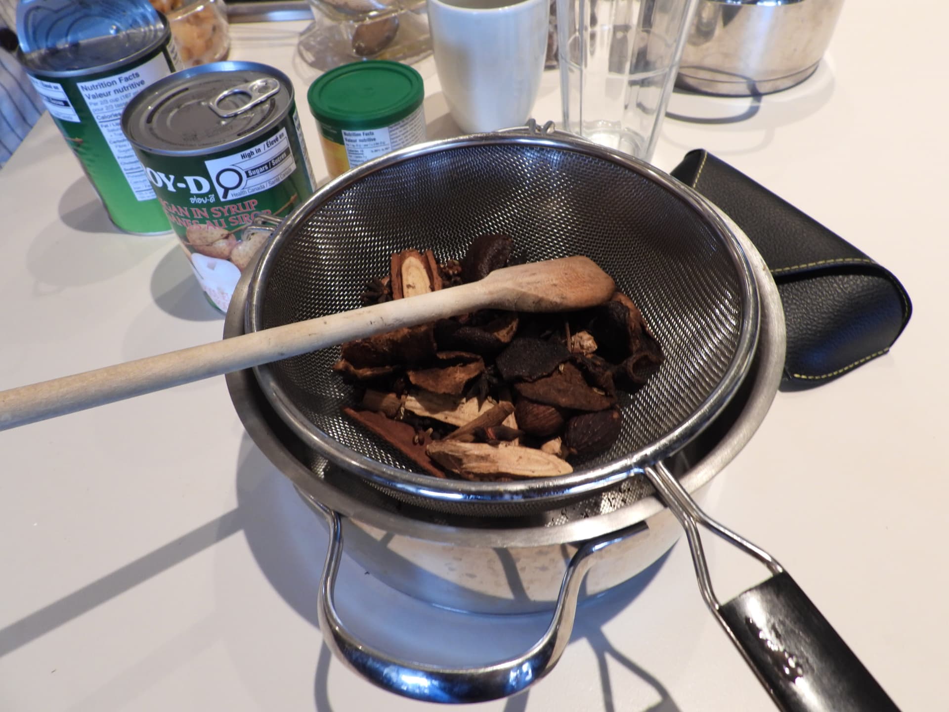 Whole spices in a sieve over a pot in the kitchen at Denter Tumas