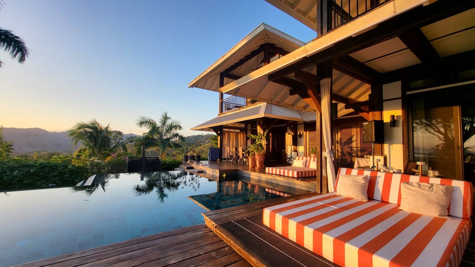 The pool at Denter Tumas at sunset, with still water reflecting the villa and lush greenery