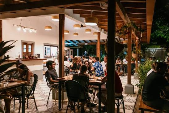 Guests dining under warm lights and a timber roof in the garden of La Quincha restaurant at night